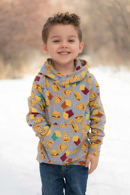 Child wearing a colorful hoodie with a pattern of shapes in a snowy landscape