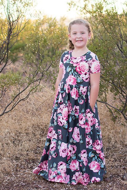 A young girl is wearing the Samantha Dress with short sleeves and a maxi length. Features a floral pattern. 