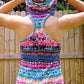 Back view of a woman wearing the Althea Racerback Tank Top with the hood up. The tank is made from a knit fabric with a pink, blue, and purple geometric pattern.