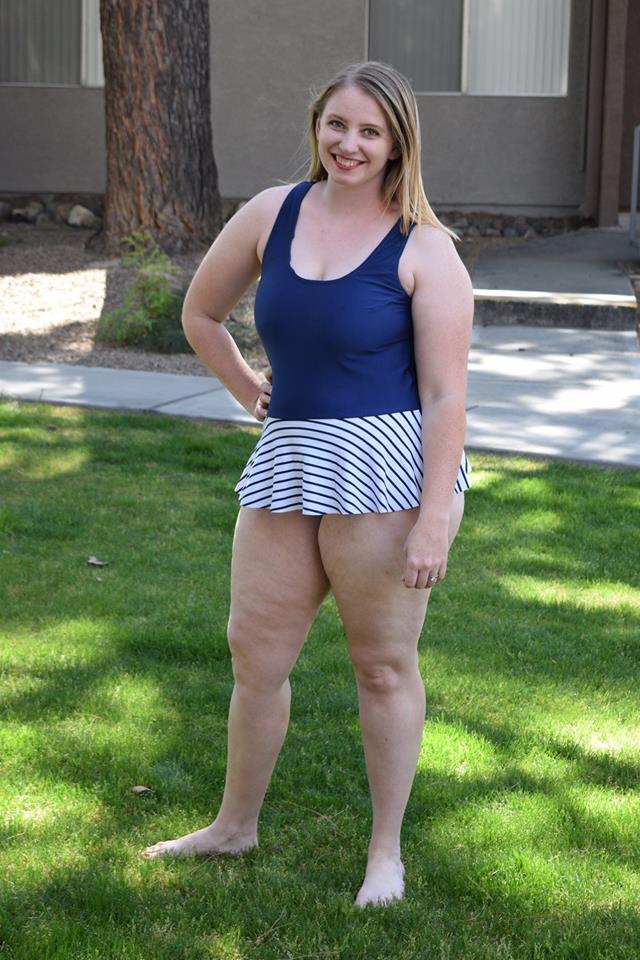 Woman wearing DIBY Club Amelia one-piece swimsuit with dark blue top and white and blue striped skirt option.