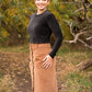 Photo of woman standing on a trail wearing a black long sleeve velvety shirt with a brown corduroy maxi-length DIBY Club Anna Button-Up Skirt