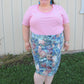 Full-length view of plus size woman wearing blue and green knee length DIBY Club Anna Button-Up skirt with dark blue buttons. Her shirt is tucked in showing the waistband.