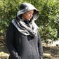Pattern tester displaying the Hooded Infinity Scarf. Hood is up. Main fabric and lining are a gray gingham. 