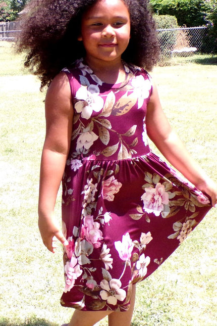 A young girl wearing a sleeveless, mid length version of the Samantha Gathered Dress. 