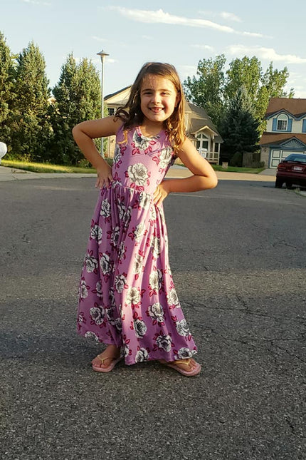 A young girl displays a sleeveless, floral themed, maxi-length Samantha Dress. 