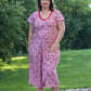 Plus size Stevie jumpsuit featuring short sleeves, wide leg, and tie waist options. Fabric is pink with blue stars. 