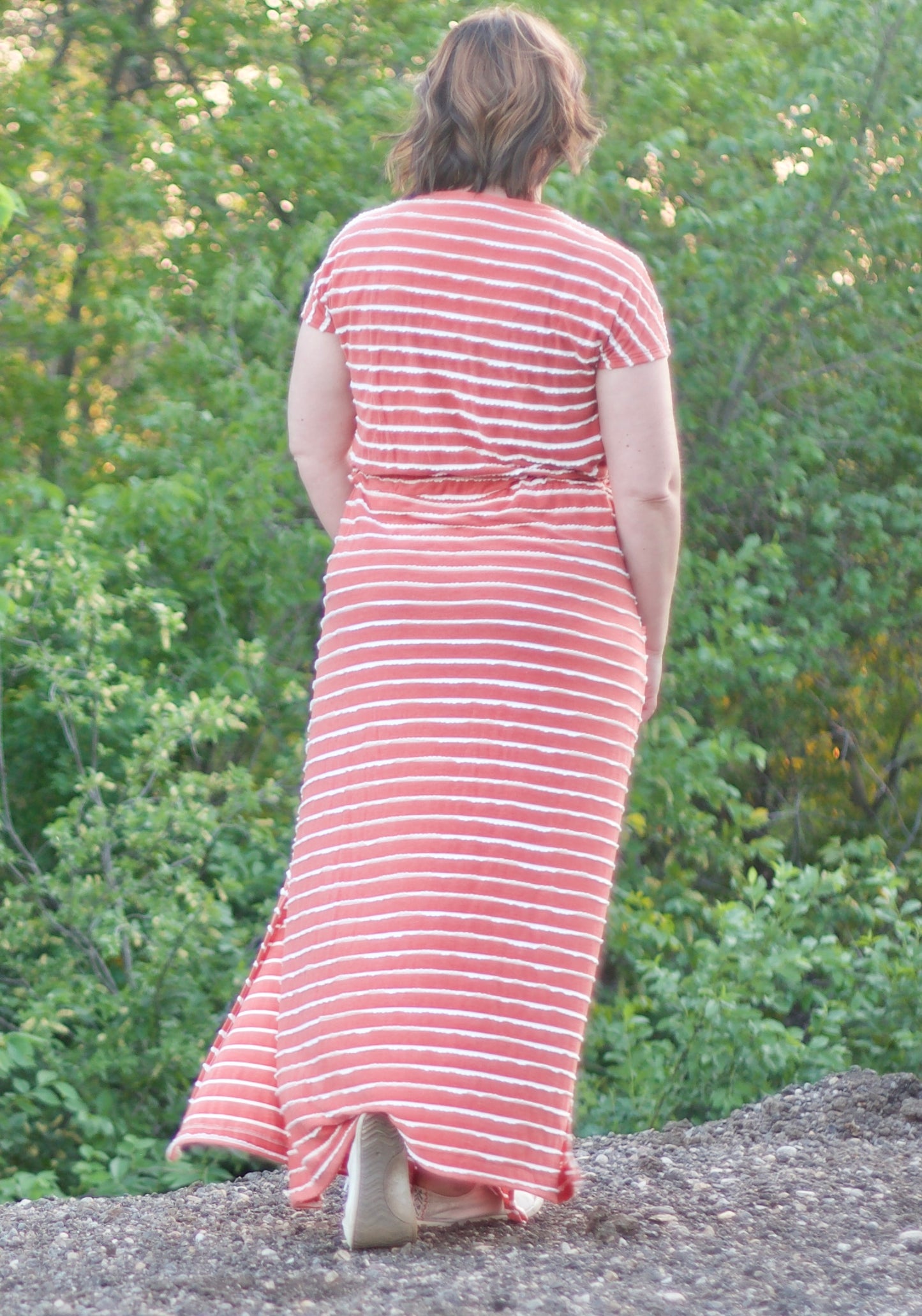 Back view of the Helen Dress in plus size. Features a maxi-length skirt with a split hem and pockets. 